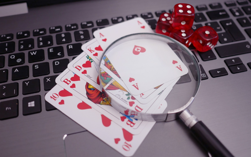 Playing Cards with a Magnifying Glass on top of a Laptop